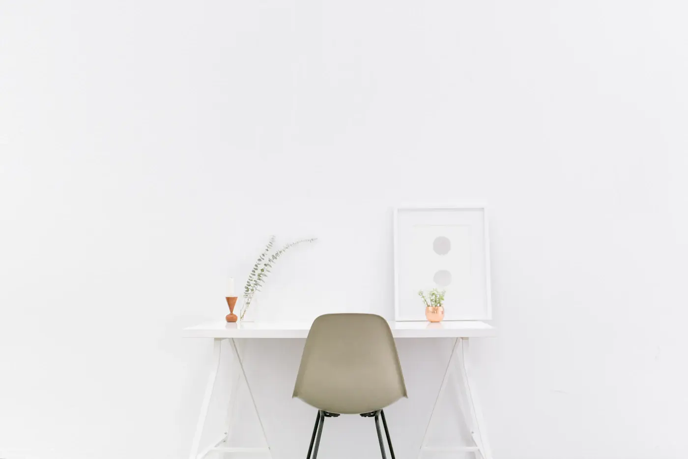 A white desk and a single chair in a bright, bare room